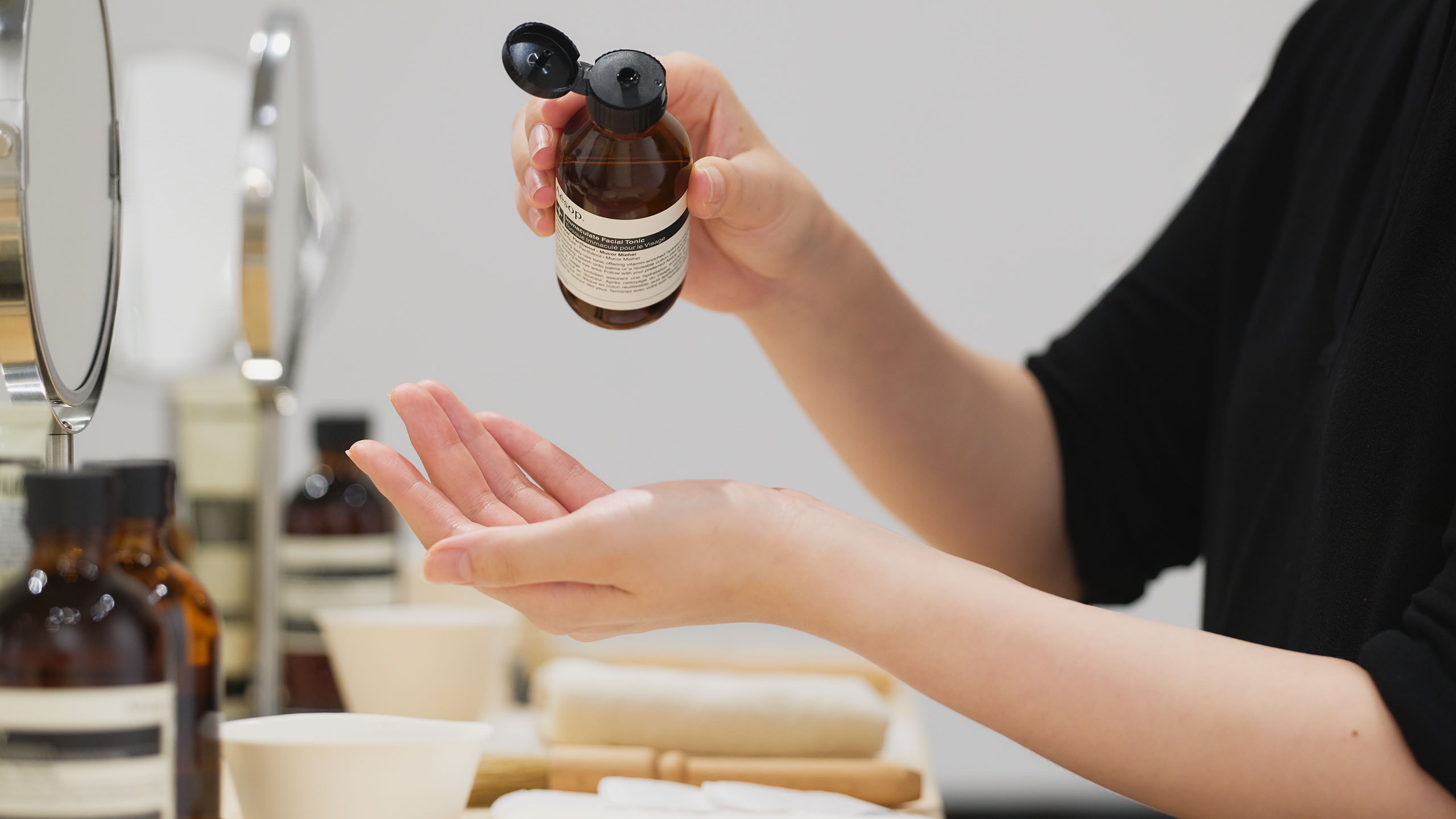 A woman pouring Immaculate Facial Tonic on her hand